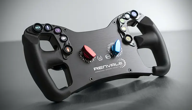 3/4 full photo of the black renvale steering wheel. You can see the two black rubber handles and black body. Yo can also see all the coloured buttons and dials. It has a white renvale logo in the centre. It is photographed on a grey stainless steel background. The Renvale R102S steering wheel is used in real GT4 motorsport the only difference with the Ascher McLaren Artura Pro SIM wheel is the CAN electronics